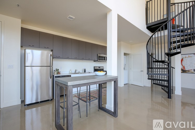 A modern kitchen with a stainless steel refrigerator and a spiral staircase.