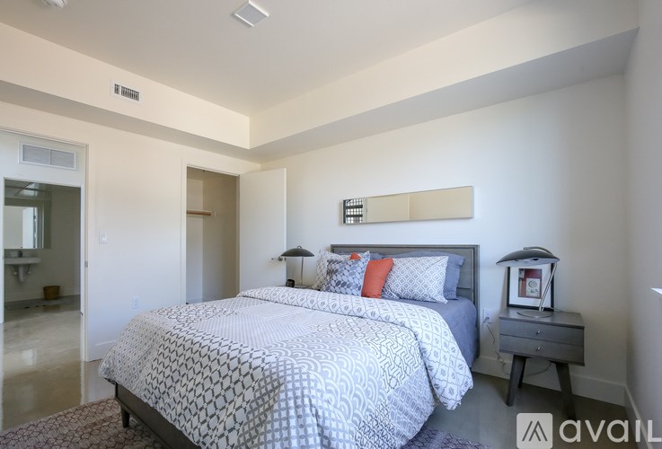 A bedroom with a large bed and a nightstand with a lamp.