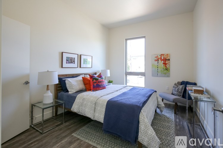 A bedroom with a bed, a couch, and a painting on the wall.