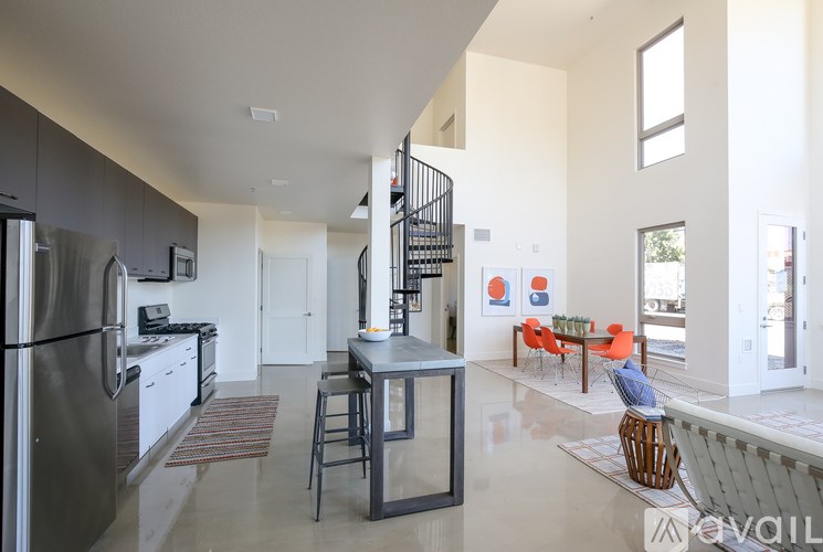 A modern kitchen with a stainless steel refrigerator and a dining area with orange chairs.