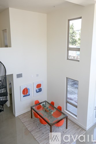 A living room with a glass table and orange chairs.