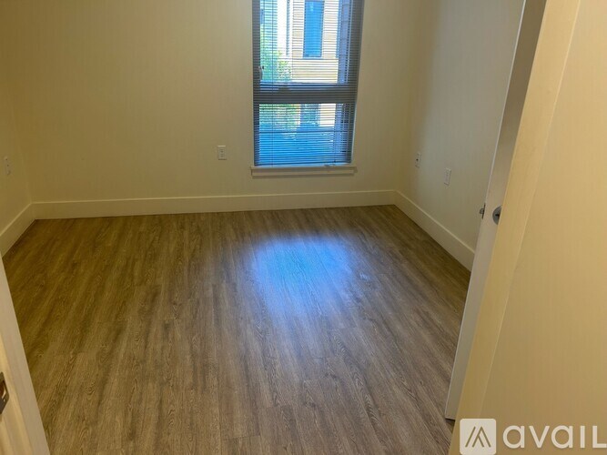 A room with wooden flooring and a window letting in natural light.
