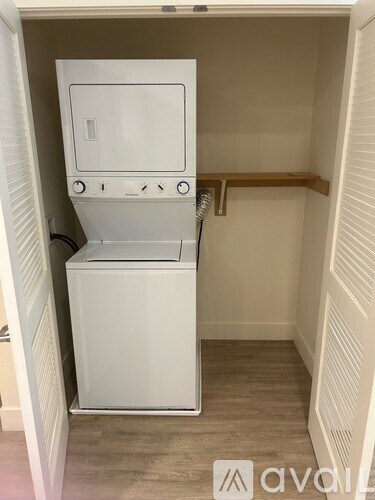 A white washing machine in a small, white-walled laundry room.