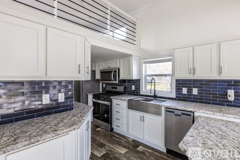 A kitchen with white cabinets and a marble countertop.
