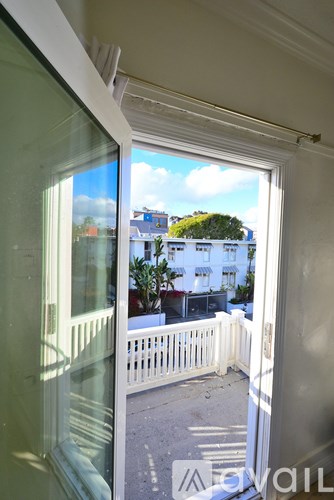 A balcony with a white railing and a view of a street with buildings.