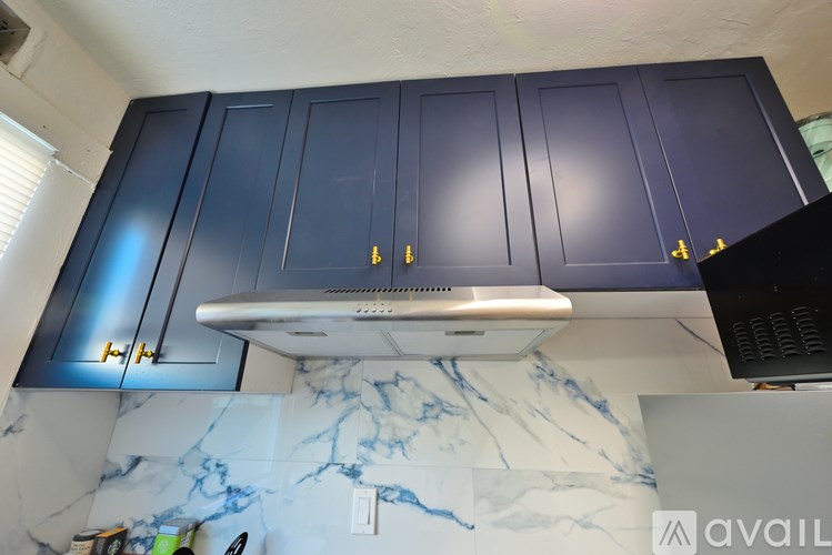 A kitchen with dark blue cabinets and a marble countertop.