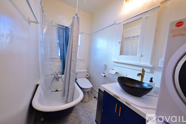 A bathroom with a black and white bathtub, a toilet, a sink, and a mirror.