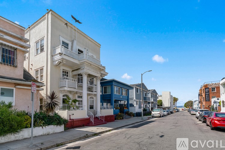 A street view with a row of buildings and cars parked on the side.