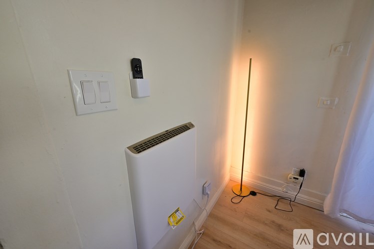A white wall with a light switch and a black remote.