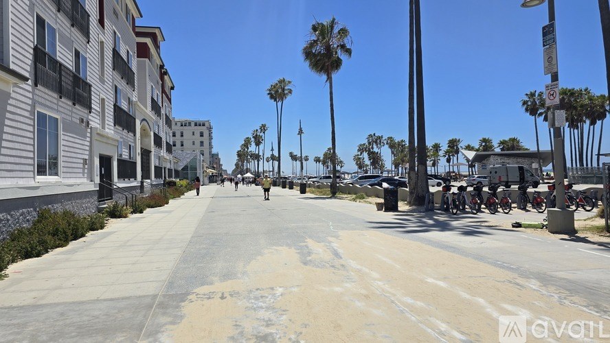 A street with palm trees and buildings on either side.