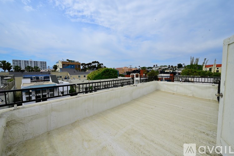 A rooftop with a white wall and a black railing.