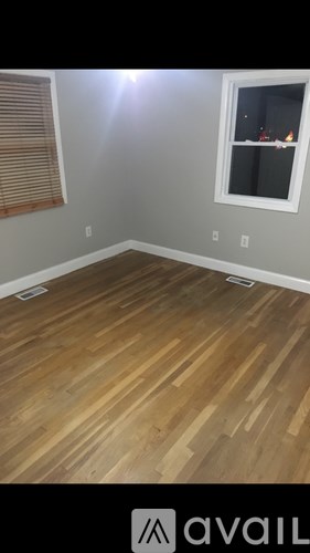 A room with wooden flooring and a window with blinds.