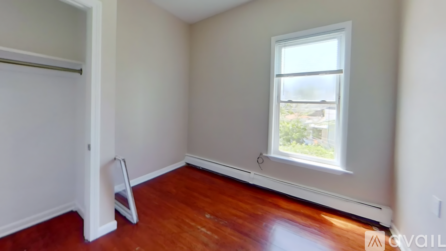 A room with a window and a wooden floor.