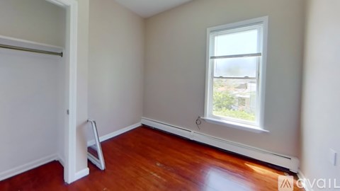 A room with a window and a wooden floor.