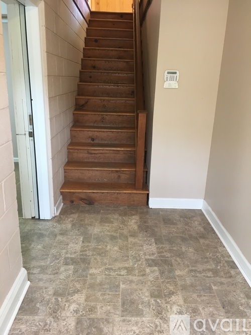 A staircase with a white wall and a calendar on it.