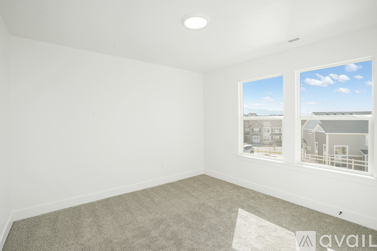 A spacious room with a carpeted floor and a large window overlooking a residential area.