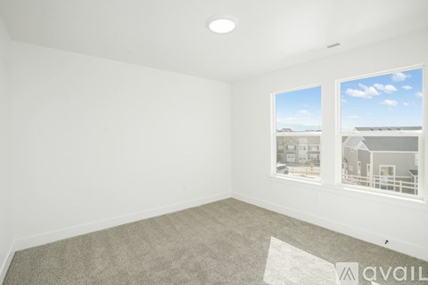 A spacious room with a carpeted floor and a large window overlooking a residential area.