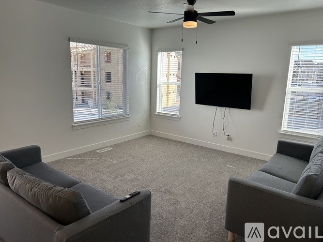 A living room with grey couches and a flat screen TV mounted on the wall.