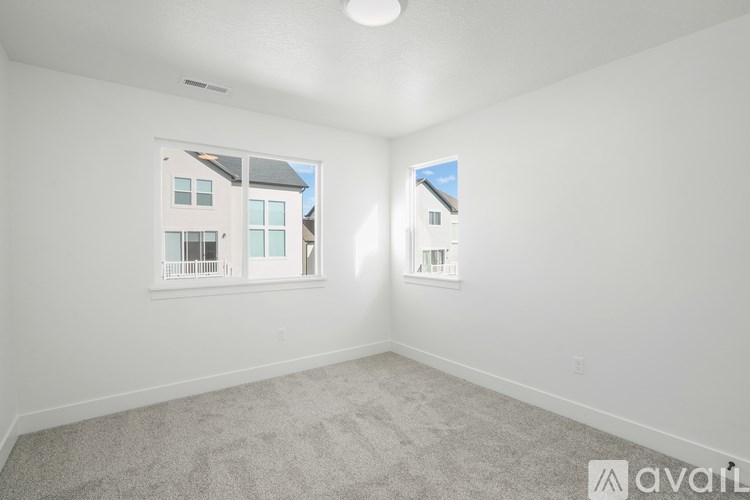 A white room with a carpeted floor and two windows.