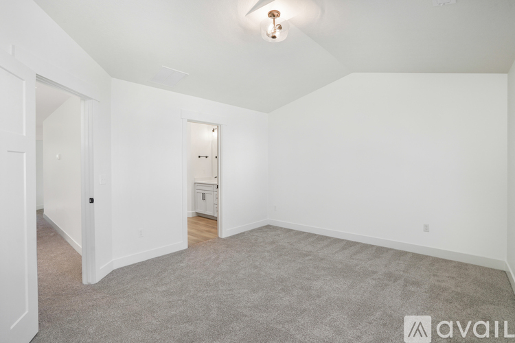 A spacious empty room with a carpeted floor and white walls.