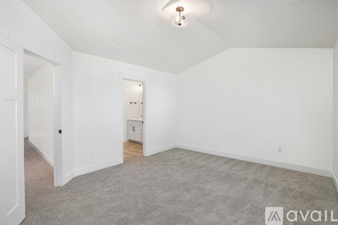 A spacious empty room with a carpeted floor and white walls.