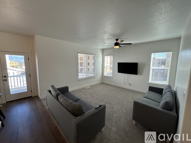 A living room with a grey couch and a television mounted on the wall.