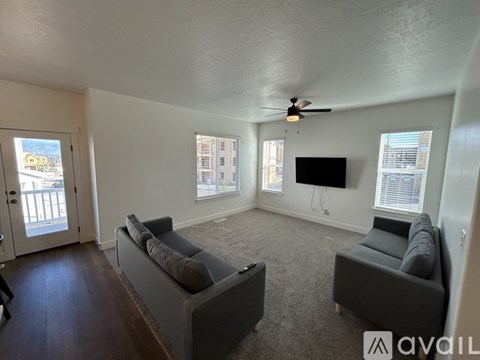 A living room with a grey couch and a television mounted on the wall.