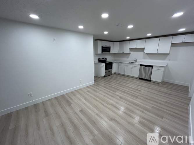 A spacious kitchen with white cabinets and a wooden floor.