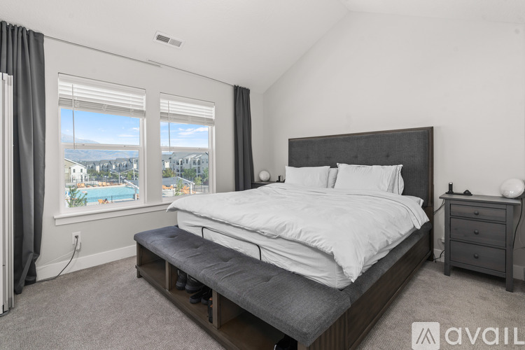 A bedroom with a large bed, a nightstand, and a window overlooking a pool.