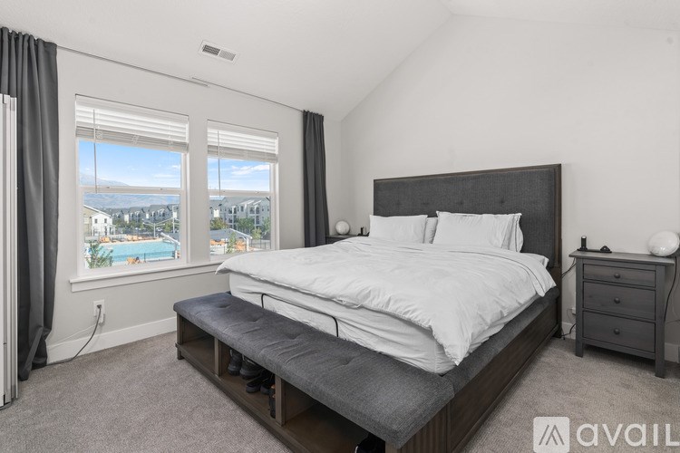 A bedroom with a large bed, a nightstand, and a window overlooking a pool.