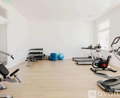 A gym with a variety of equipment including a stationary bike, a rowing machine, and a weight bench.