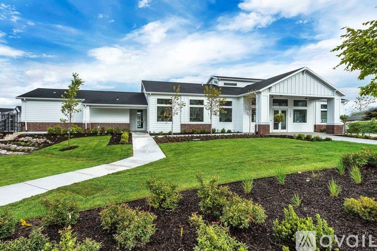 A white house with a black roof and a garden in front.