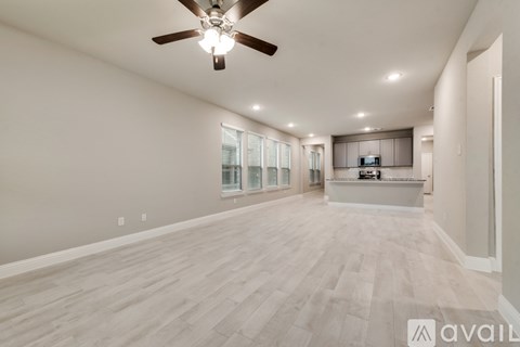 A spacious living room with a ceiling fan and lighting fixture.