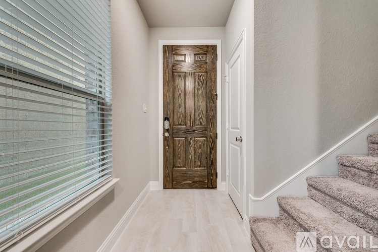 A hallway with a wooden door and stairs.
