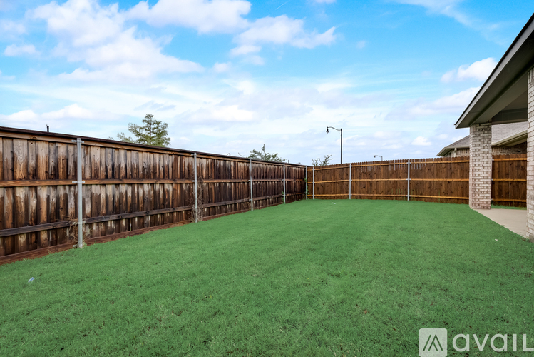 A backyard with a wooden fence and green grass.