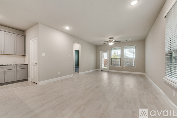 A spacious room with light wood flooring and a ceiling fan.