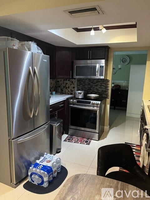 A kitchen with a stainless steel refrigerator and a black chair.