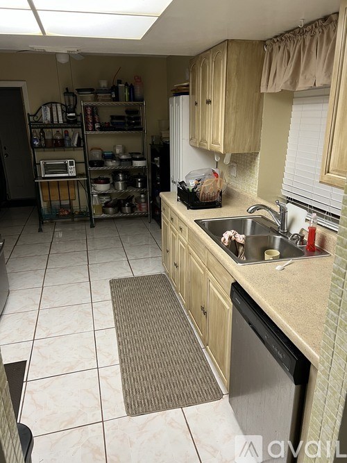 A kitchen with a sink, a dish rack, and a window.