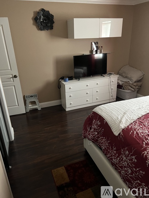A bedroom with a bed, dresser, and television.