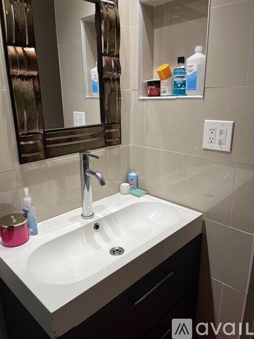 A bathroom sink with a mirror above it and a shelf with bottles on it.