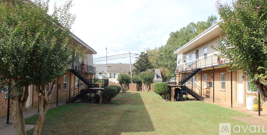 A grassy area between two buildings with a tree on the left.