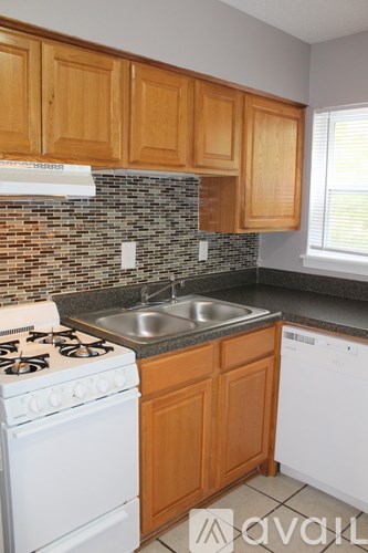 A kitchen with a white stove and wooden cabinets.