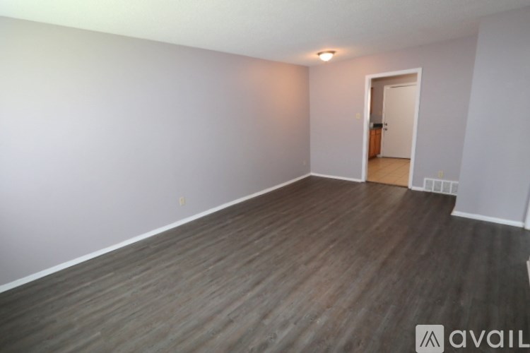 A room with wooden flooring and a doorway leading to another room.
