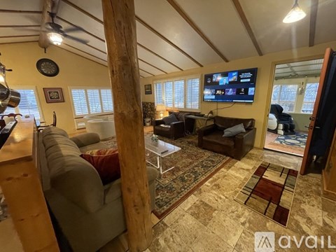 A living room with a couch, a chair, and a television mounted on the wall.