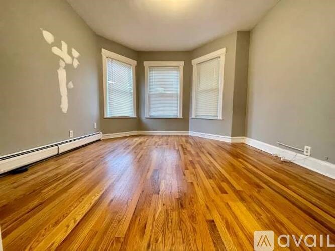 A room with wooden flooring and two windows.