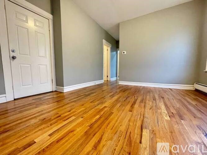 A room with wooden flooring and a white door.