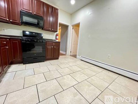 A kitchen with brown cabinets and a black stove top oven.