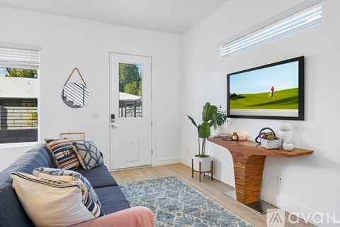 A living room with a blue couch and a television on the wall.