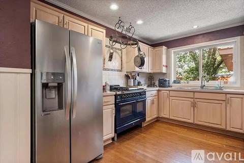 A kitchen with a stainless steel refrigerator and wooden cabinets.