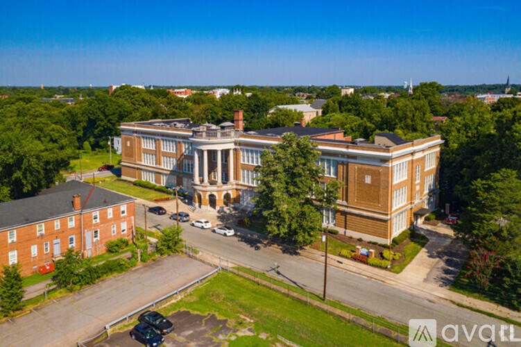 An aerial view of a large red brick building with a parking lot in front.